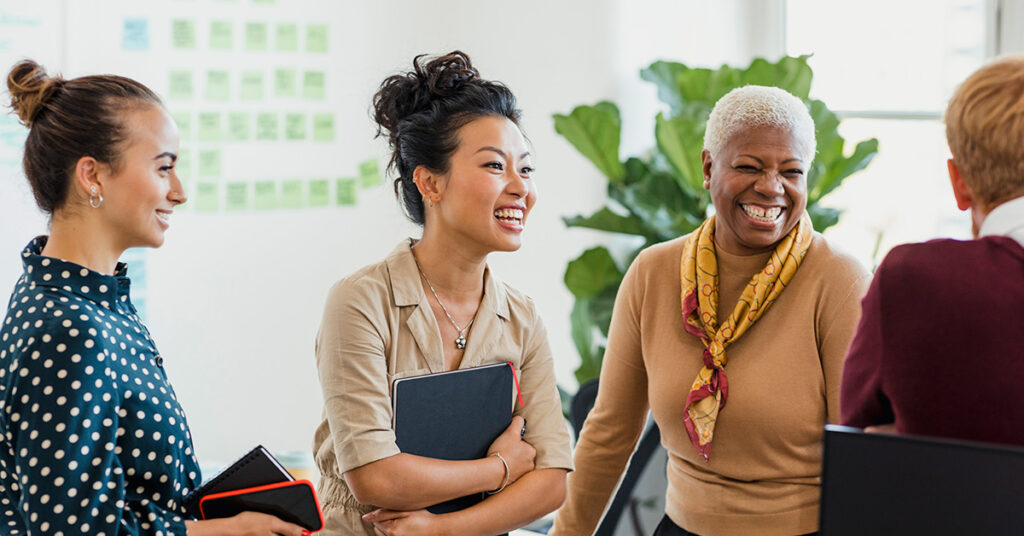 Diverse group of women in an office laughing.